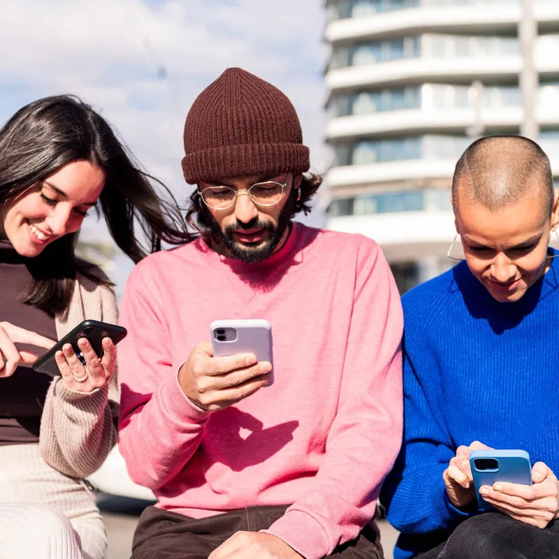 Junge Menschen sitzen zusammen und sind am Smartphone. Junge Menschen sitzen zusammen und sind am Smartphone.