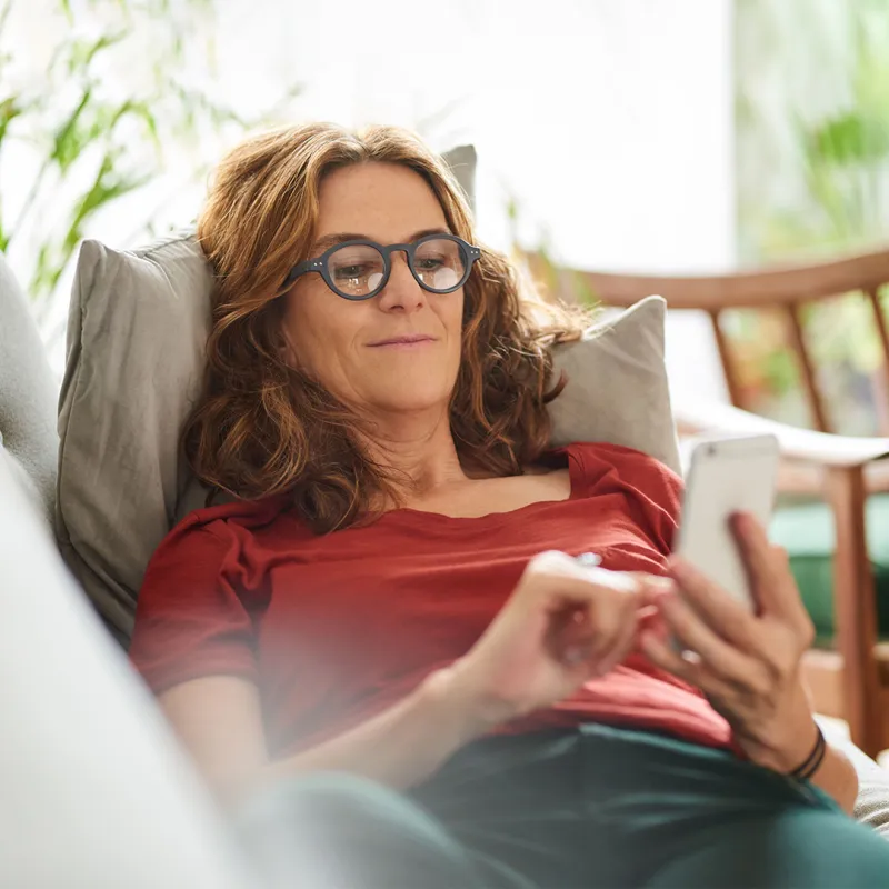 Frau mit Smartphone in der Hand auf Couch. Frau mit Smartphone in der Hand auf Couch.